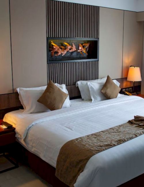A neatly arranged hotel room with a large bed, bedside lamps, and decorated walls, showcasing a cozy and inviting atmosphere.