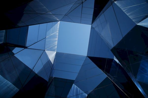 Geometric glass and steel structures form a futuristic architectural design, with a central clear sky visible through the top opening.