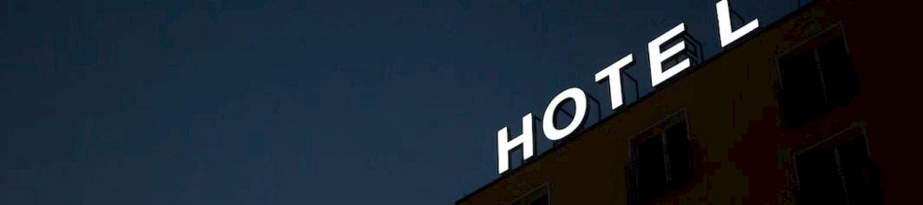 A building with a partially illuminated "HOTEL" sign against a dark sky.