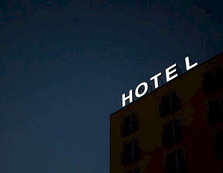 A building with a partially illuminated "HOTEL" sign against a dark sky.