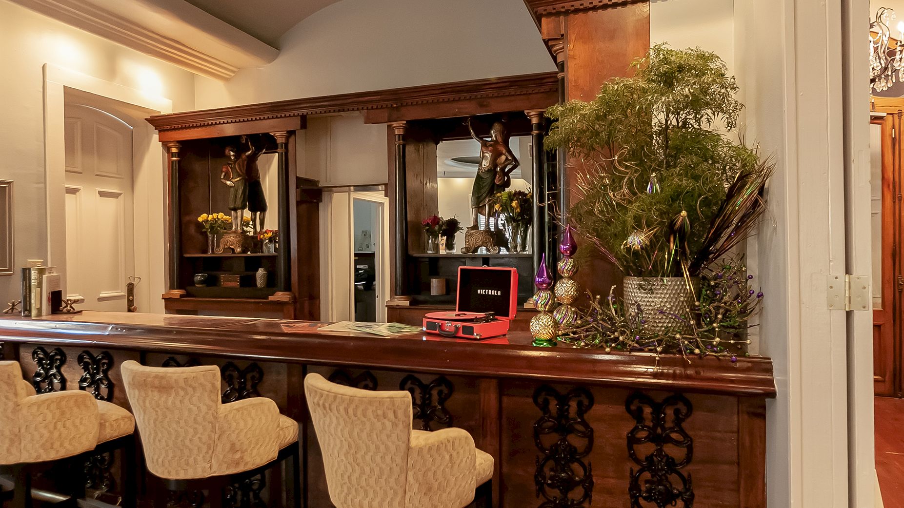a lobby bar with a wooden counter, three bar chairs, a record player, and plants