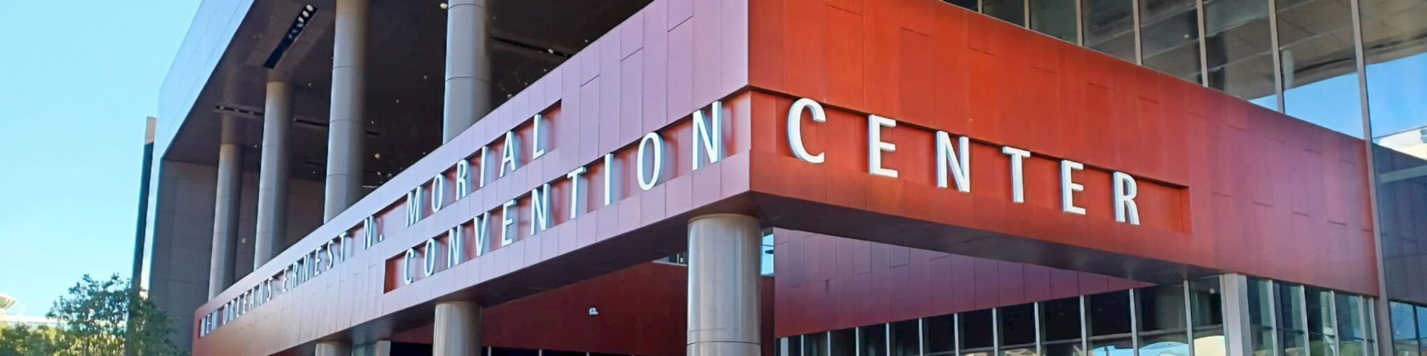 This image shows the exterior of a large convention center with modern architecture and a red-brown facade.