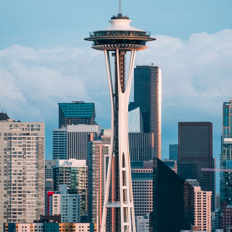 The image shows the Seattle skyline with the Space Needle prominently in the foreground, surrounded by modern skyscrapers and buildings.